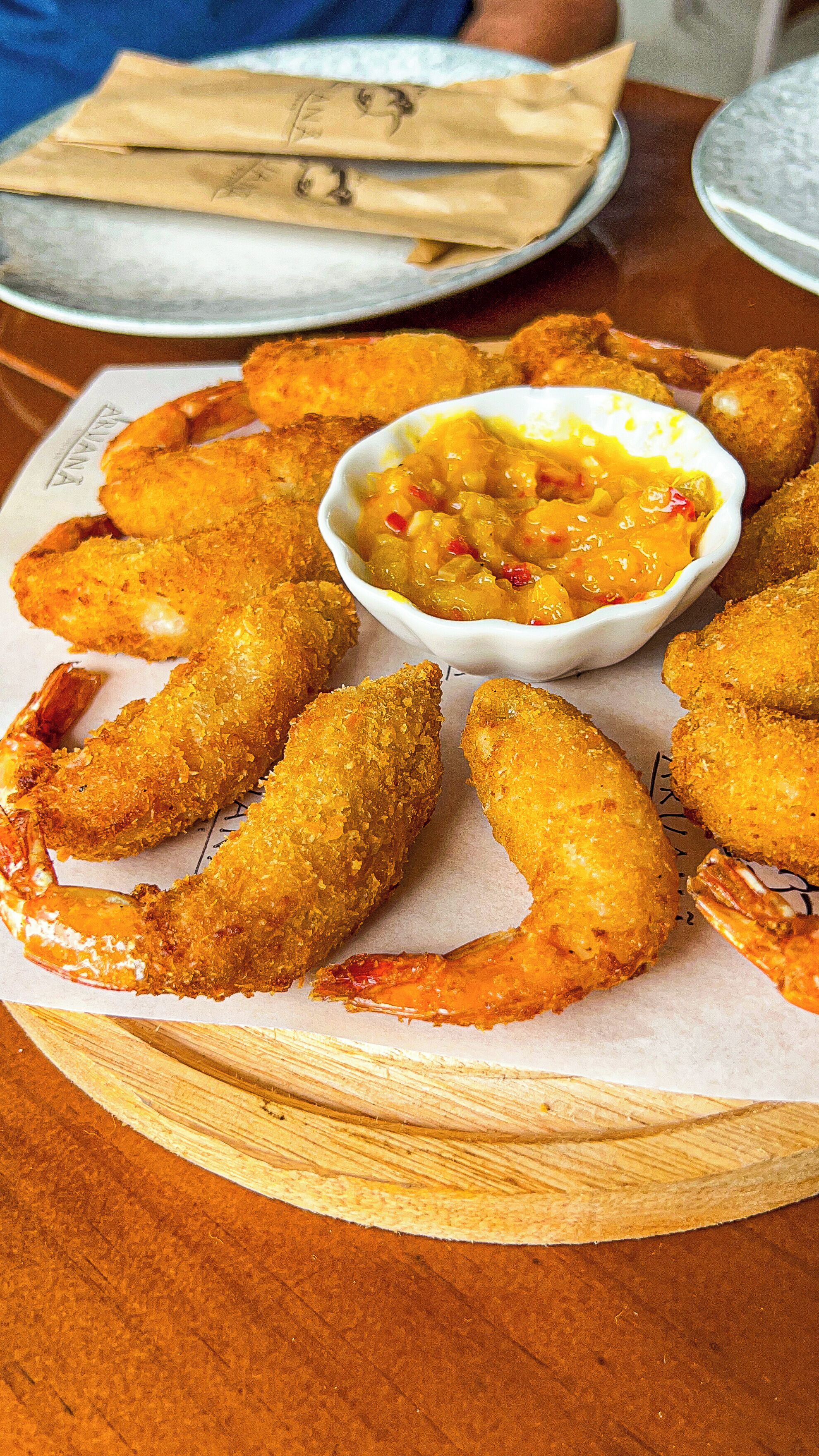 Une assiette de crevettes panées et frites, accompagnée d'une sauce pour tremper.