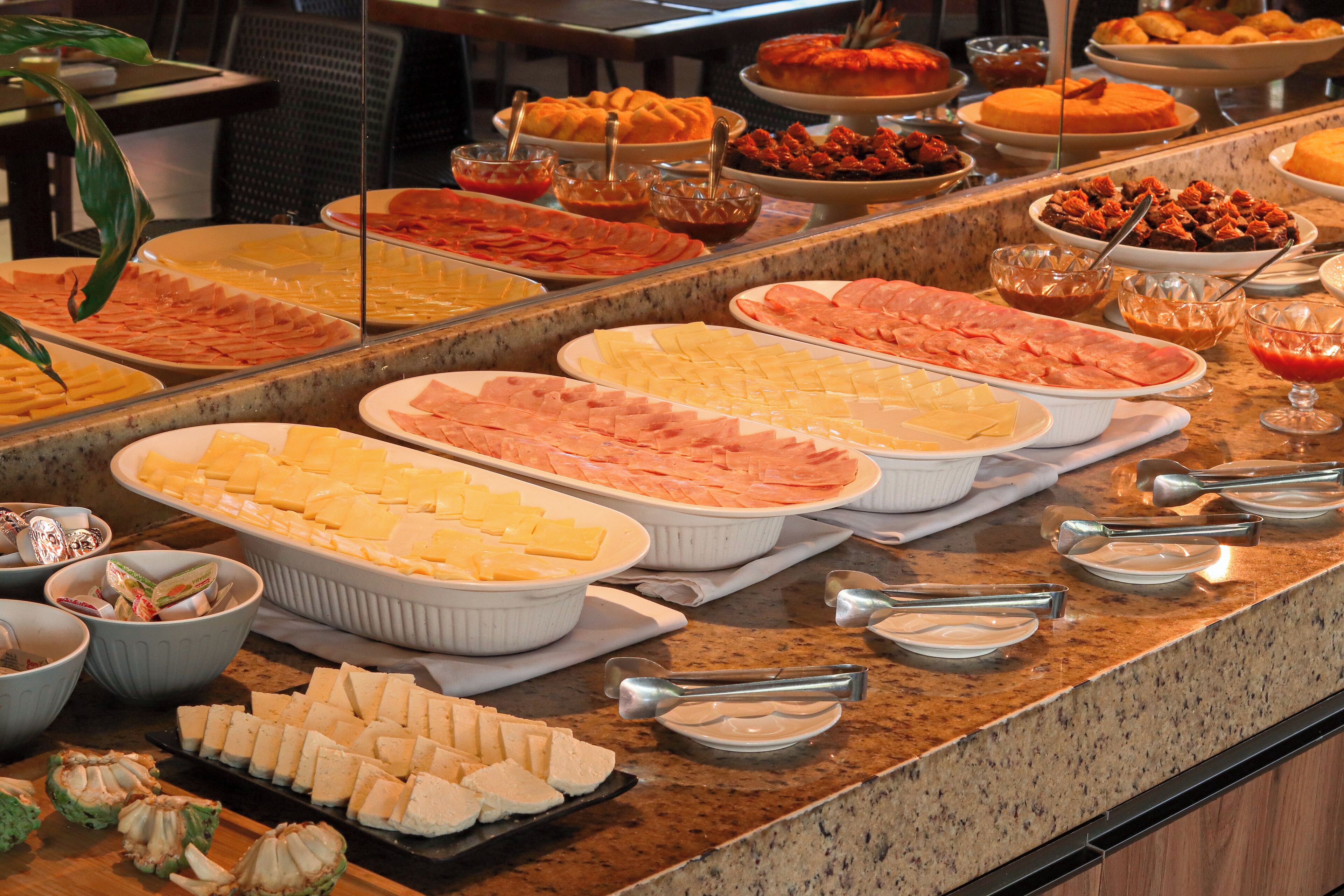 A buffet with various food items including meats, cheeses, and fruits.