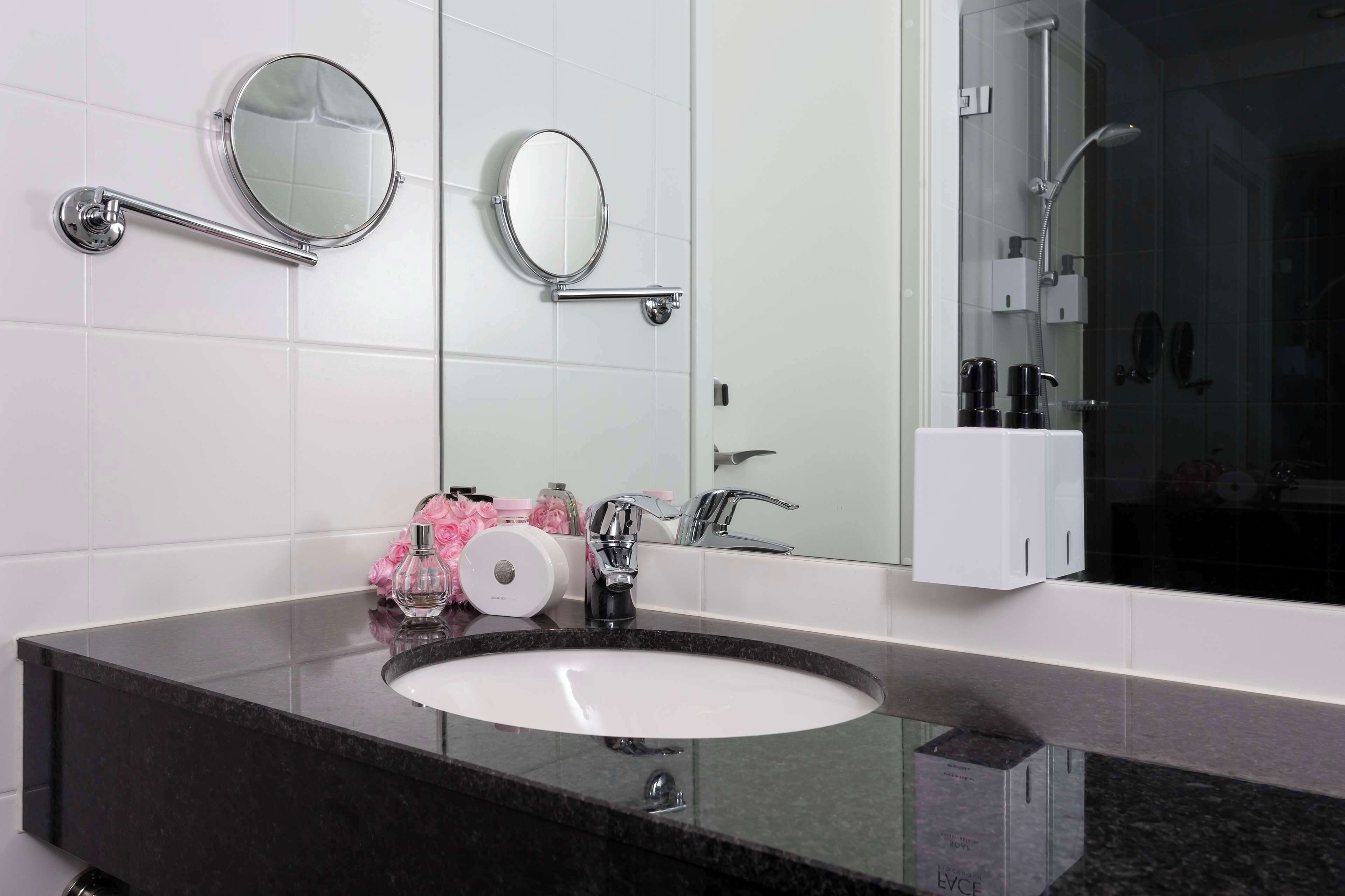 Un baño con un espejo redondo, un lavabo y una zona de ducha.