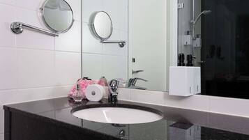 Un baño con un espejo redondo, un lavabo y una zona de ducha.