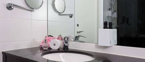 Un baño con un espejo redondo, un lavabo y una zona de ducha.