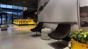 A modern lobby with a seating area, a reception desk, and a large wall mural. - Scandic Rock City (Namsos)