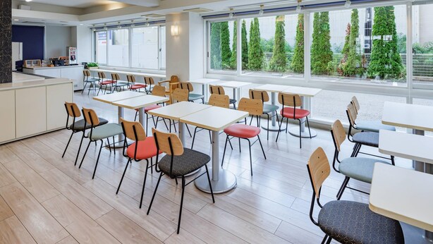 A modern dining area with multiple tables and chairs, large windows with a view of greenery, and a clean, bright interior. - Comfort Inn Suwa Inter (Suwa)