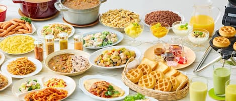 Una variedad de platos y bebidas sobre una mesa, como pasta, sopa, gofres y jugo.