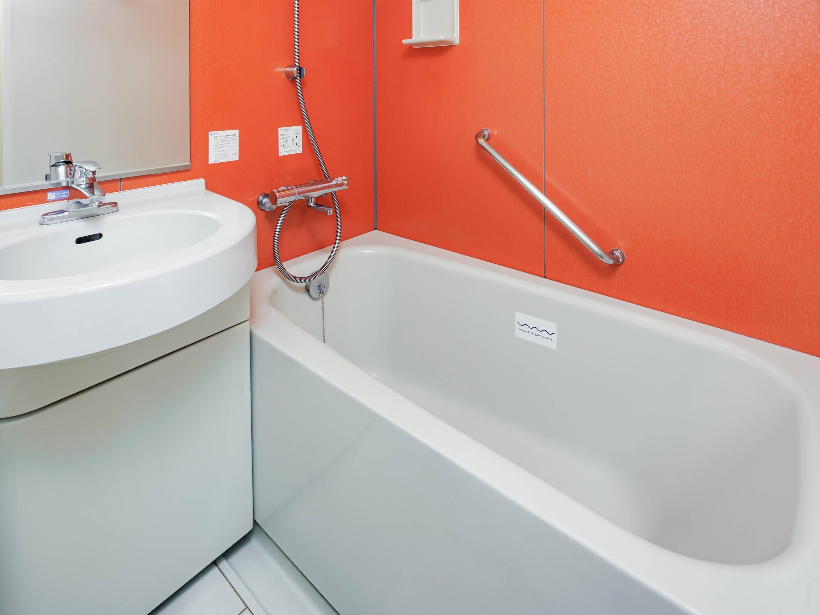 A bathroom with a white sink, a bathtub, and a handrail.