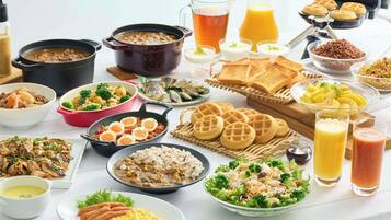 A variety of breakfast dishes including waffles, scrambled eggs, and a bowl of salad.