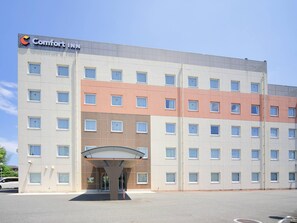 A multi-story hotel with a flat facade, a prominent entrance with a canopy, and a sign reading "Comfort INN". - Comfort Inn Munakata (Munakata)