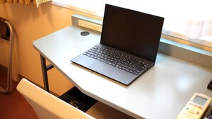 Una computadora portátil sobre un escritorio con un pequeño dispositivo a la derecha.
