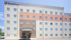 Un hotel de varios pisos con fachada plana, una entrada destacada con toldo y un letrero que dice "Comfort INN".