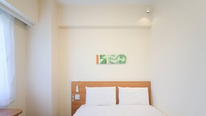 Habitación de hotel con una cama, cabecera de madera, una mesita y un aplique en la pared.