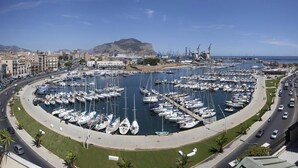Un puerto deportivo con numerosos barcos amarrados en una distribución circular, rodeado por una carretera y edificios.
