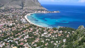 Un pueblo costero con playa, casas y una montaña.