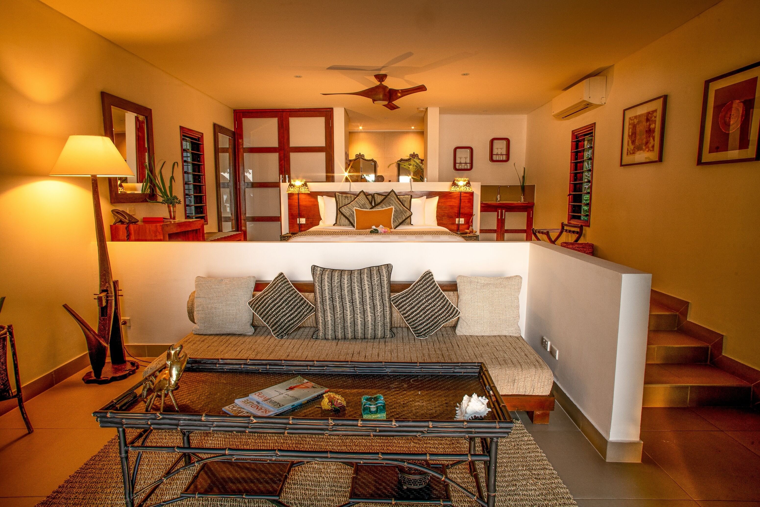 A hotel room with a bed, a sofa, a coffee table, and a staircase.
