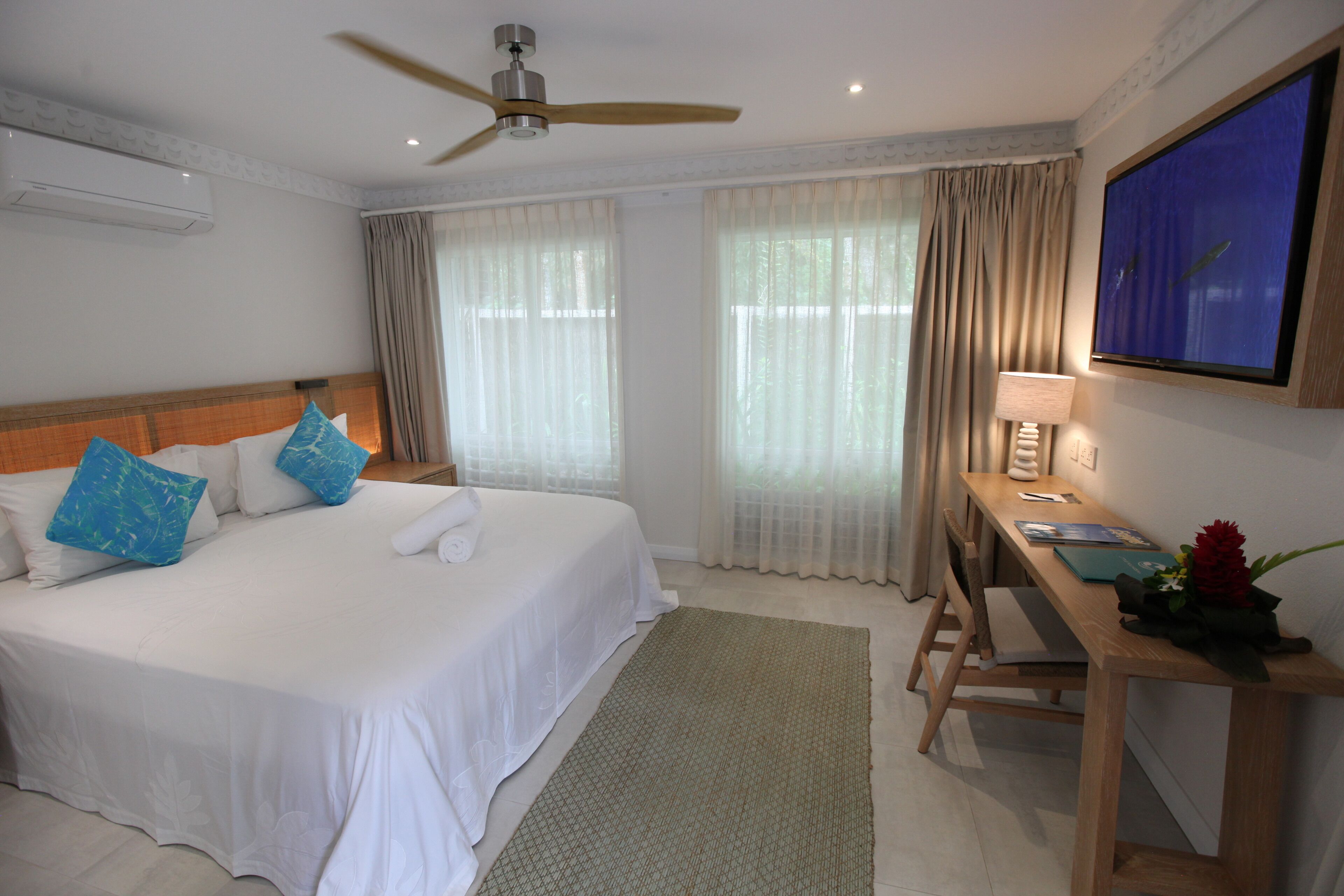 A hotel room with a bed, a desk, a television, and curtains.