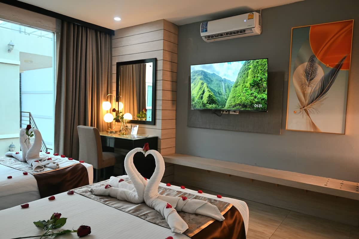 A hotel room with a bed, a desk, a TV, and a wall-mounted air conditioner.