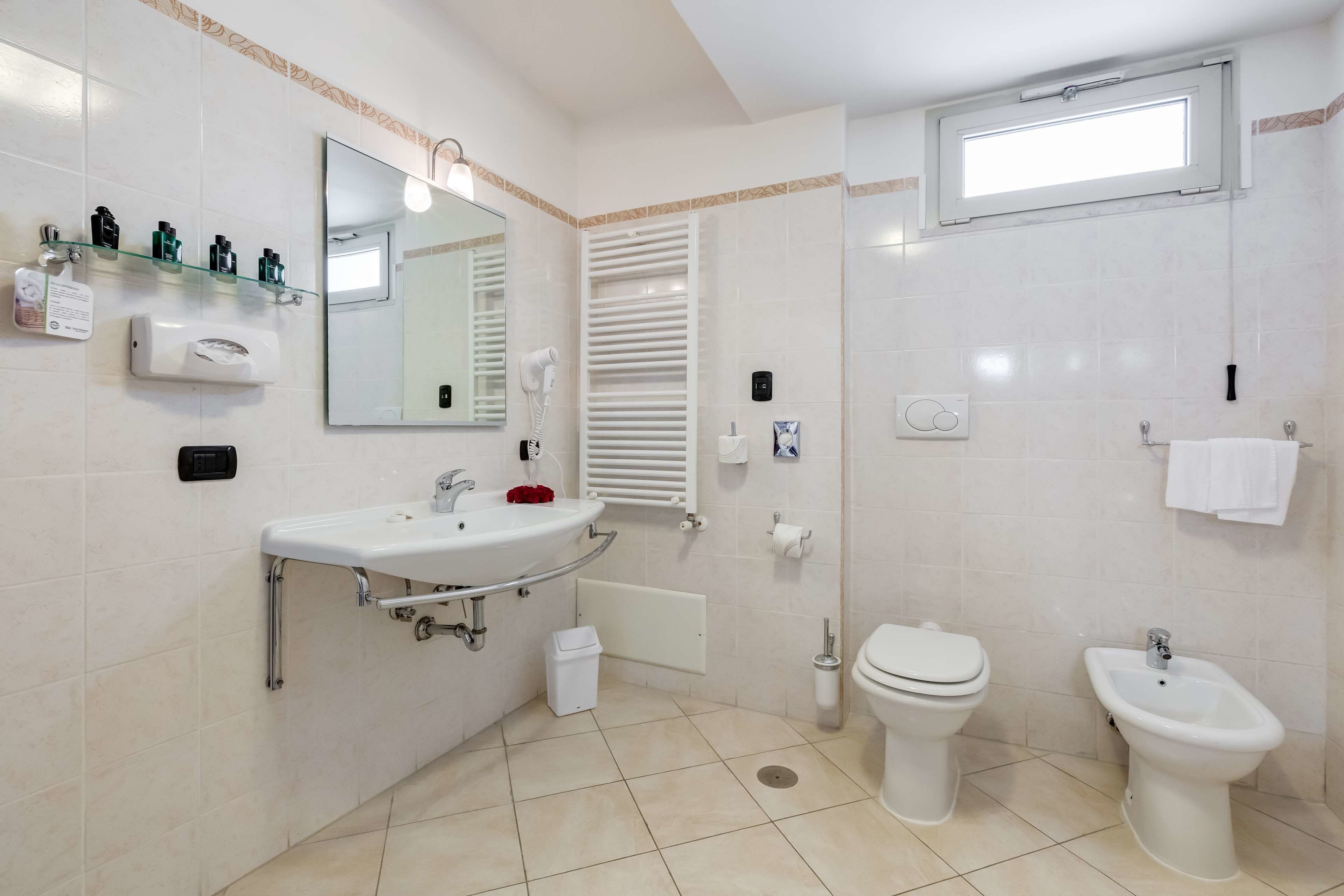 A modern bathroom with a sink, toilet, bidet, and a mirror.