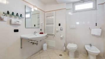 A modern bathroom with a sink, toilet, bidet, and a mirror.