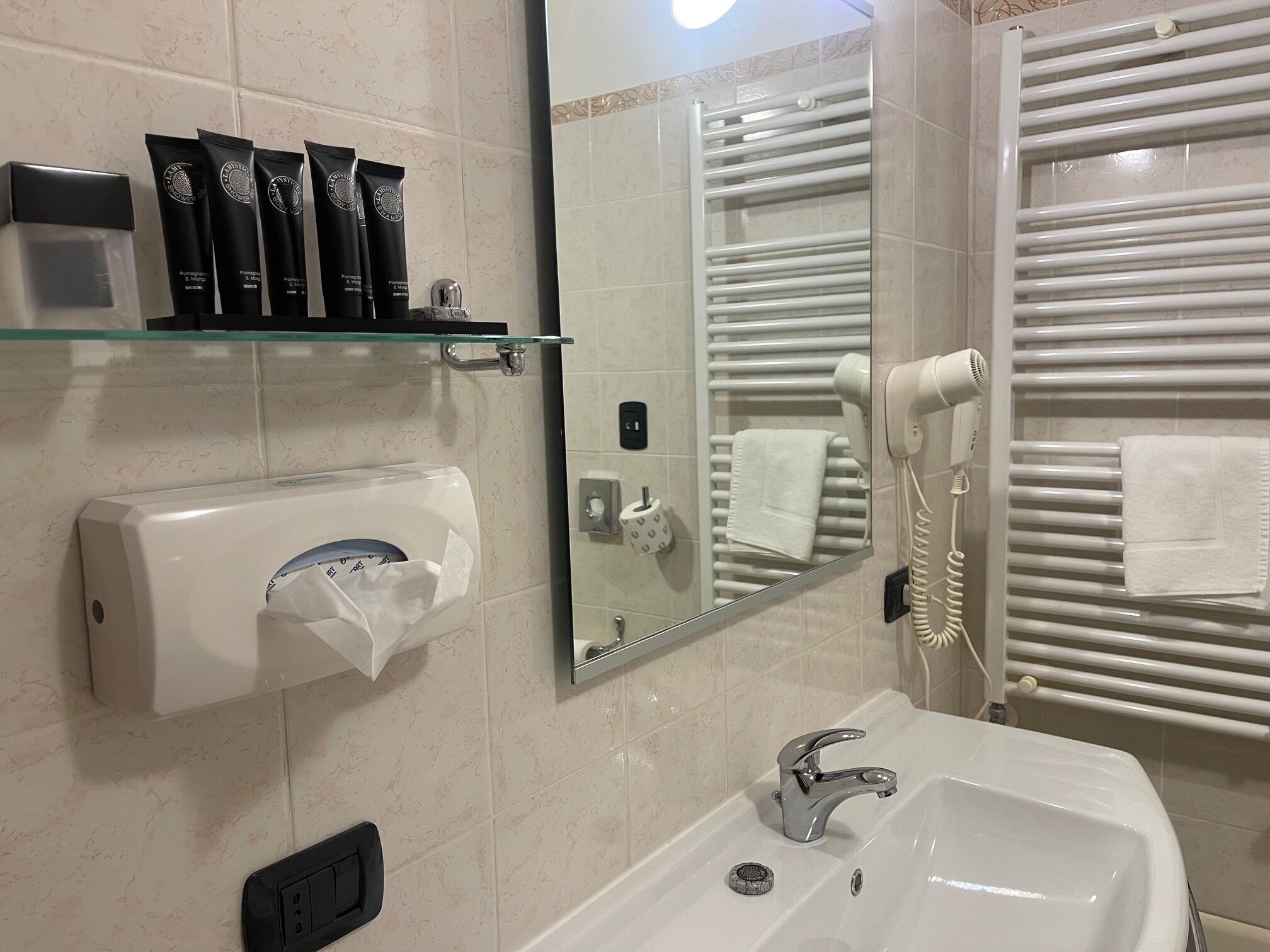 Un baño con lavamanos, espejo, toallero y secador de pelo.