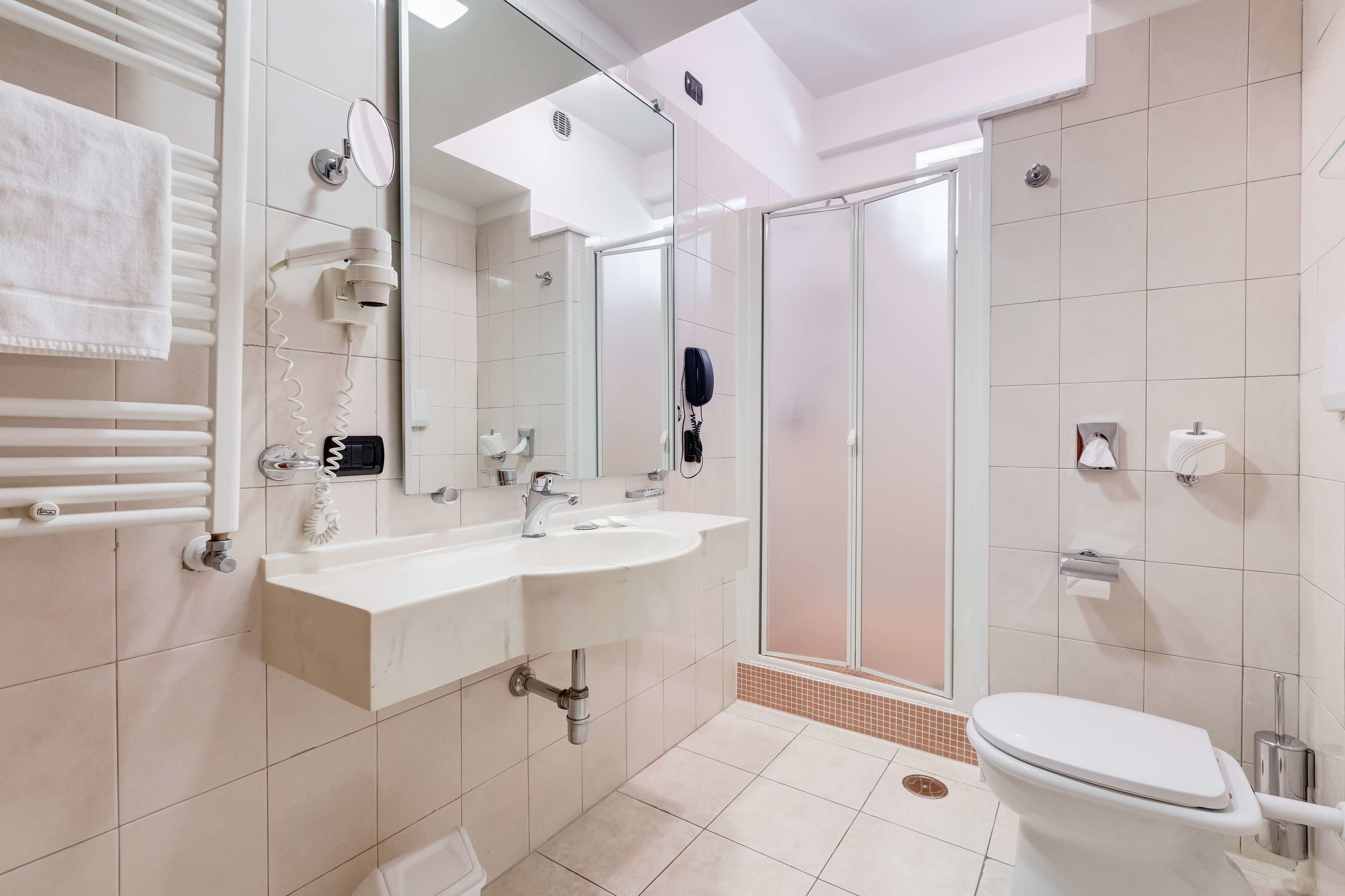 A modern bathroom with a white sink, mirror, and toilet.