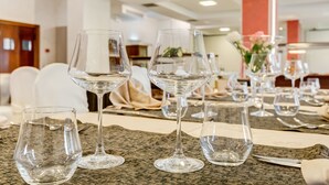 A dining area with tables set for a meal, featuring clear glassware and a woven placemat.