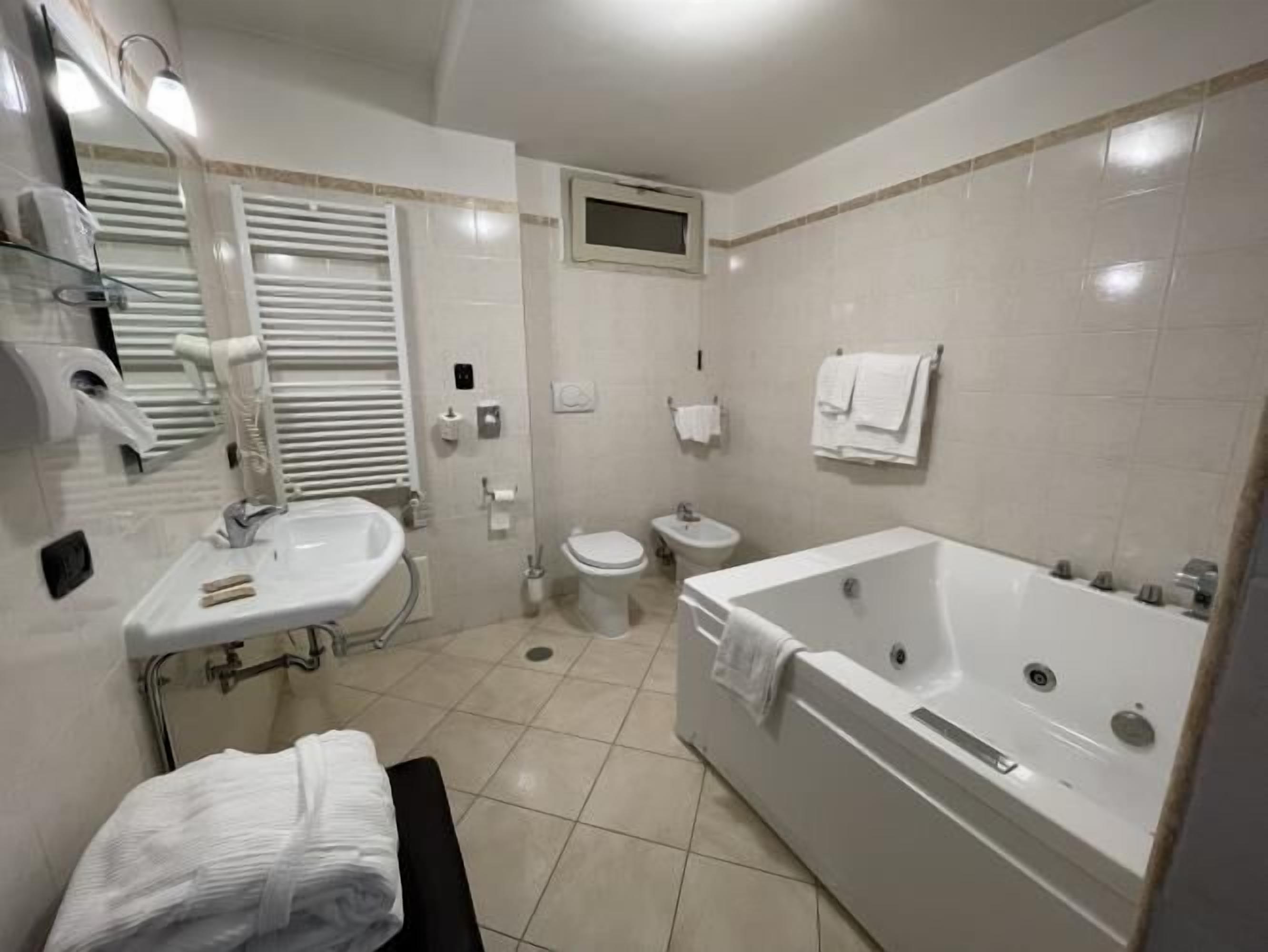 Ein modernes Badezimmer mit Badewanne, Toilette, Waschbecken und Spiegel.