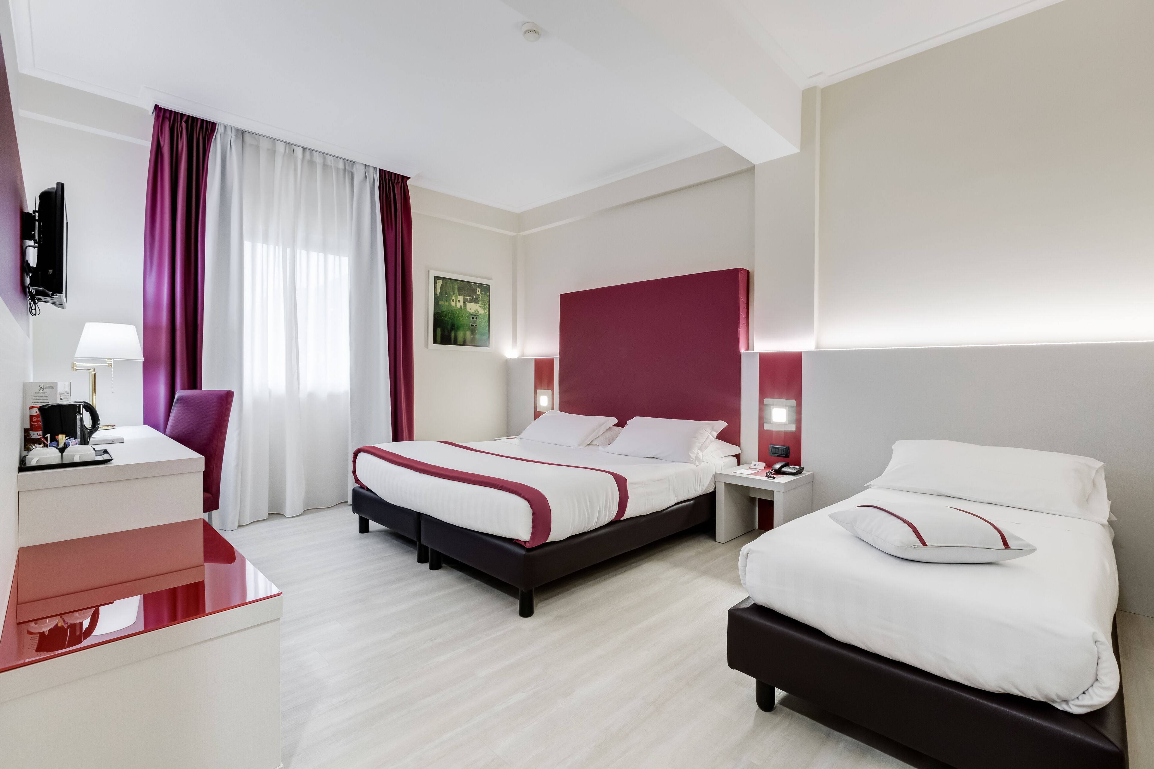 A modern hotel room with a large bed, a desk, and a chair.