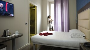 A hotel room with a bed, a bedside table with a phone and a kettle, a TV on the wall, and a bathroom with a shower and a toilet. - Hotel Five (Milan)