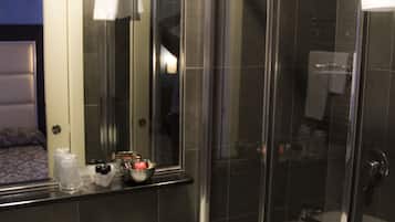 Ein Badezimmer mit einem weißen Waschbecken, einem Spiegel und einer Duschkabine.
