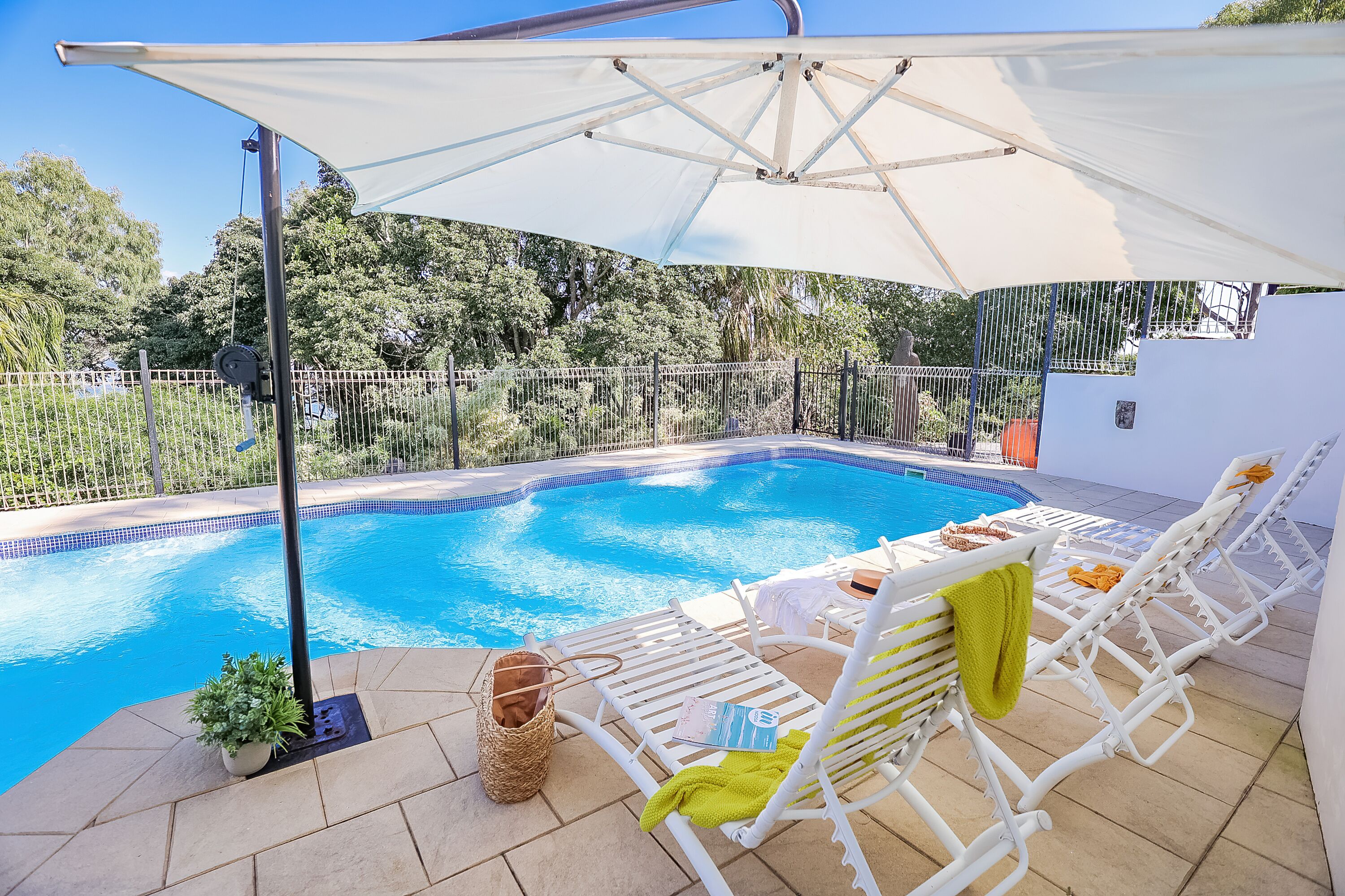 Ein Swimmingpool mit weißen Liegestühlen und einem großen Sonnenschirm.