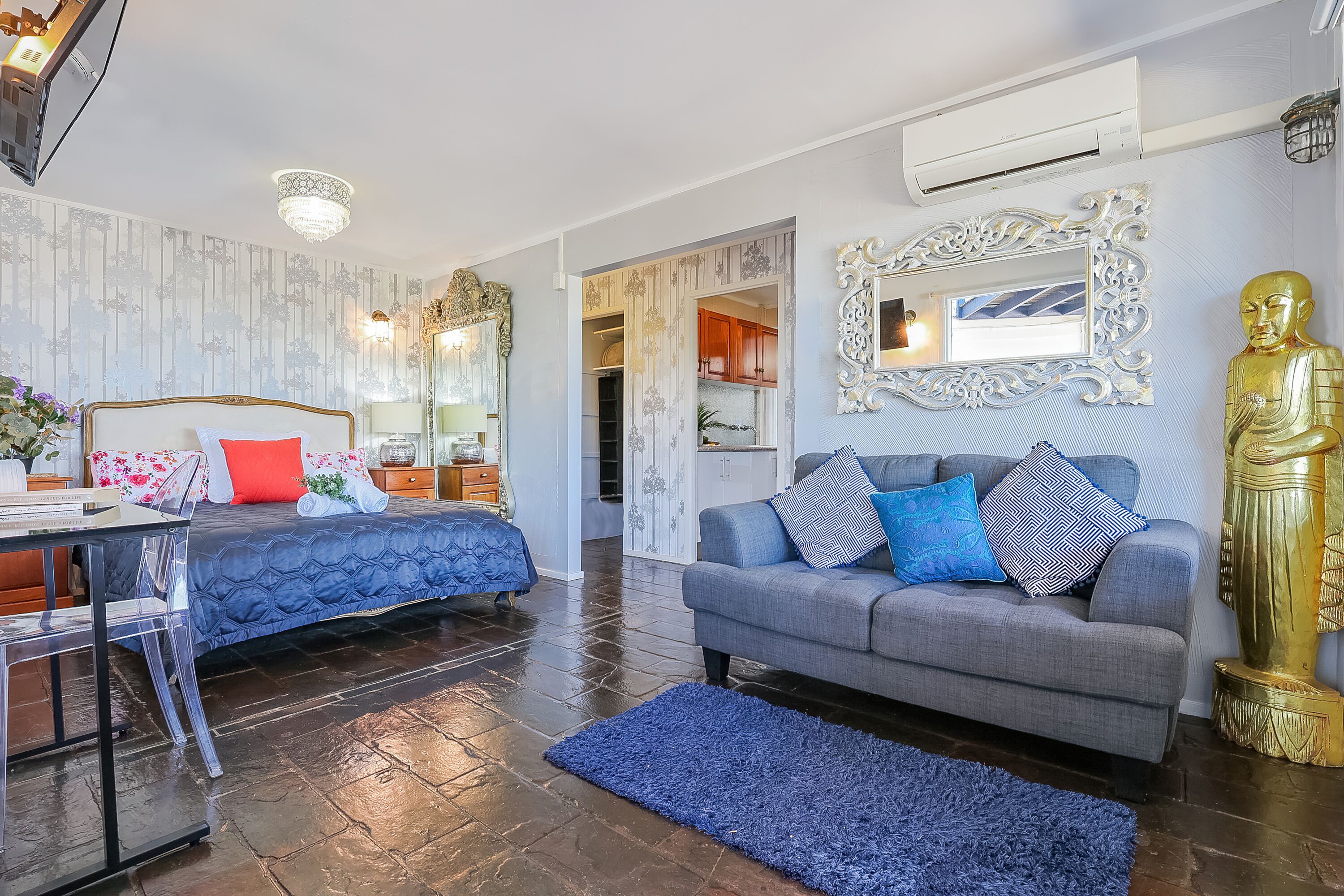 Ein modernes Wohnzimmer mit einer Couch, einem Bett, einem Schreibtisch und einer goldenen Statue.