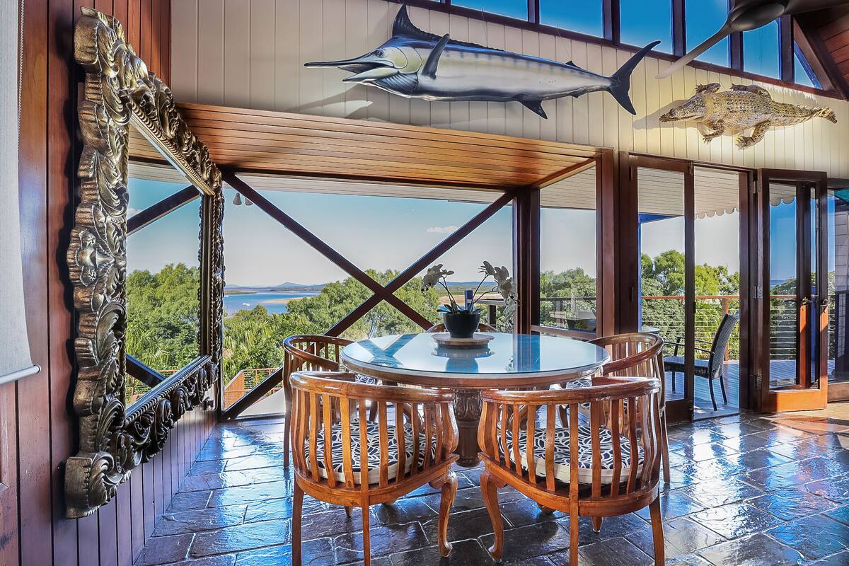 A dining area with a round table and chairs, a view of the outdoors, and decorative fish mounted on the ceiling.