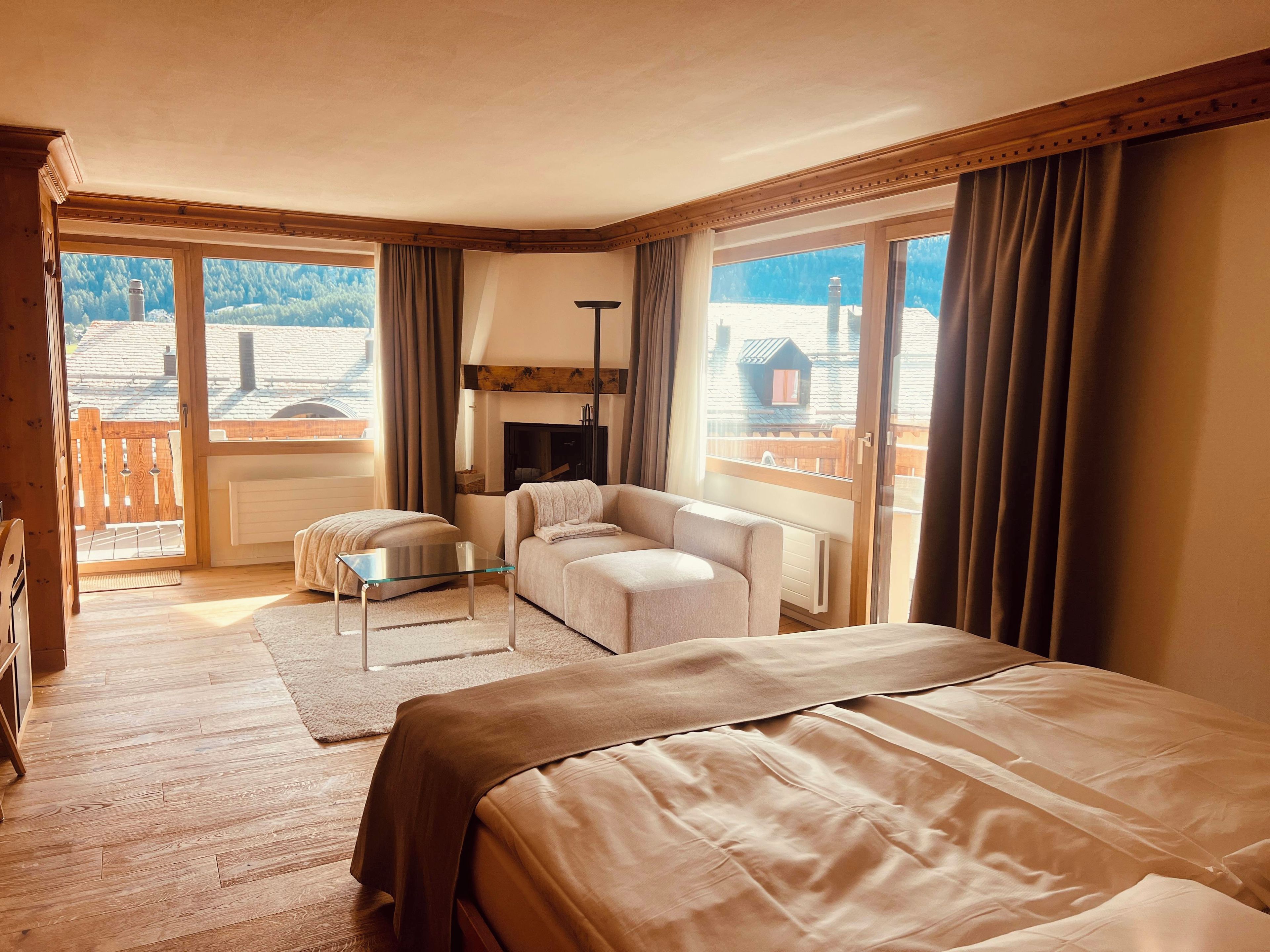 Une chambre d’hôtel avec un lit, un canapé, une petite table et une cheminée.