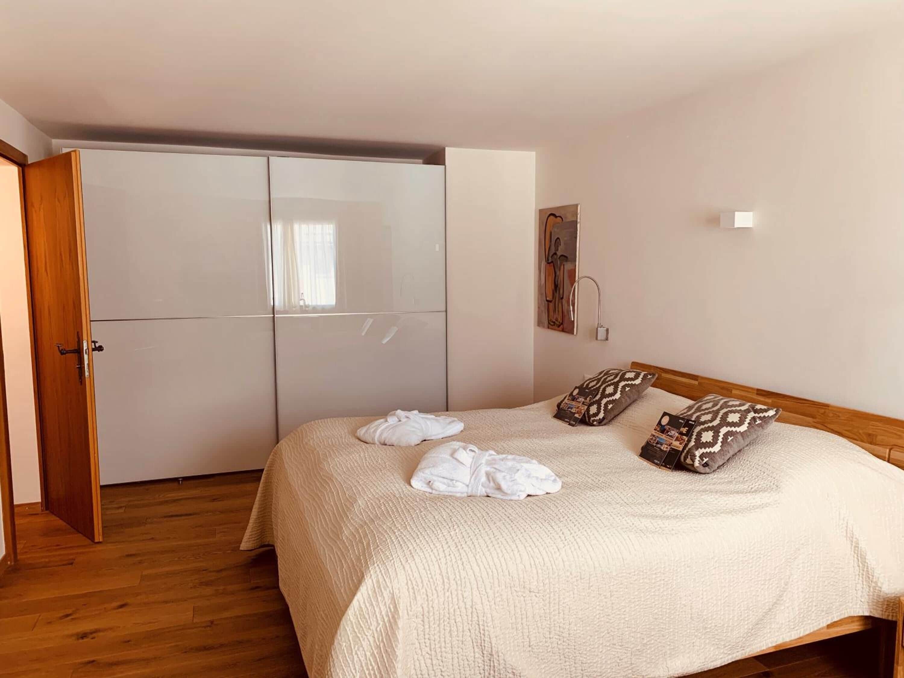 Ein Schlafzimmer mit Bett, Holzboden, Kleiderschrank und einem Bild an der Wand.