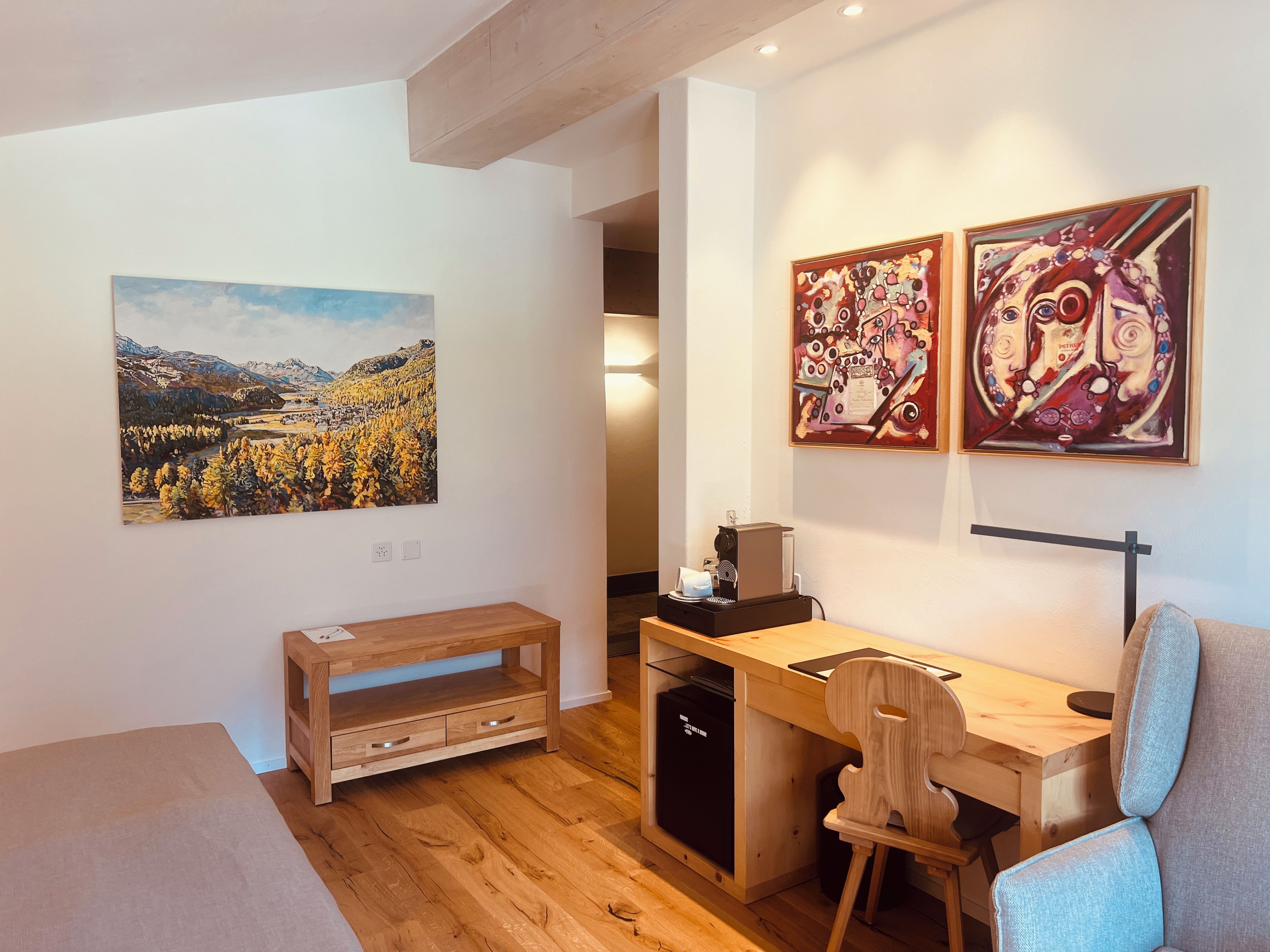 Una habitación moderna con un escritorio de madera, una silla y obras de arte en las paredes.
