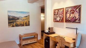 Una habitación moderna con un escritorio de madera, una silla y obras de arte en las paredes.
