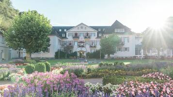 A large, stately building with a symmetrical facade, a central entrance, and a formal garden with various flower beds.