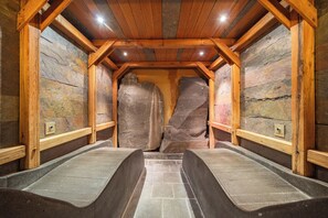 Een sauna met stenen wanden, houten balken en banken.