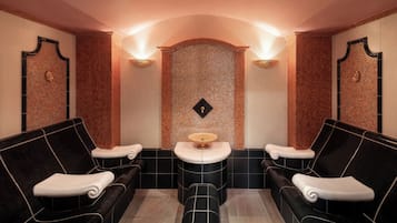 Een spa-ruimte met twee zwarte banken, een centrale wastafel en een mozaïekwand.