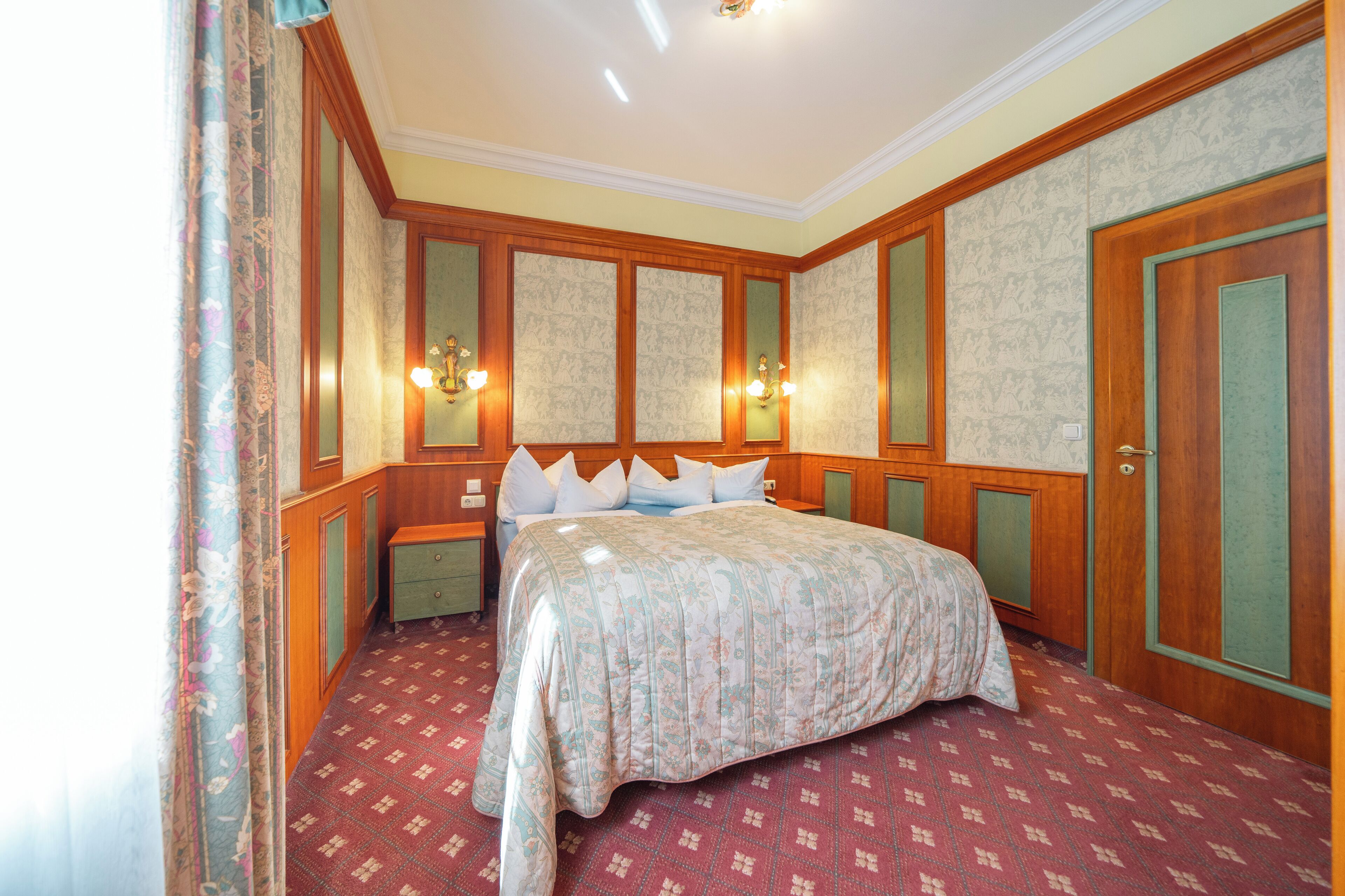 Une chambre à coucher avec un lit, des tables de chevet, une commode et une porte.