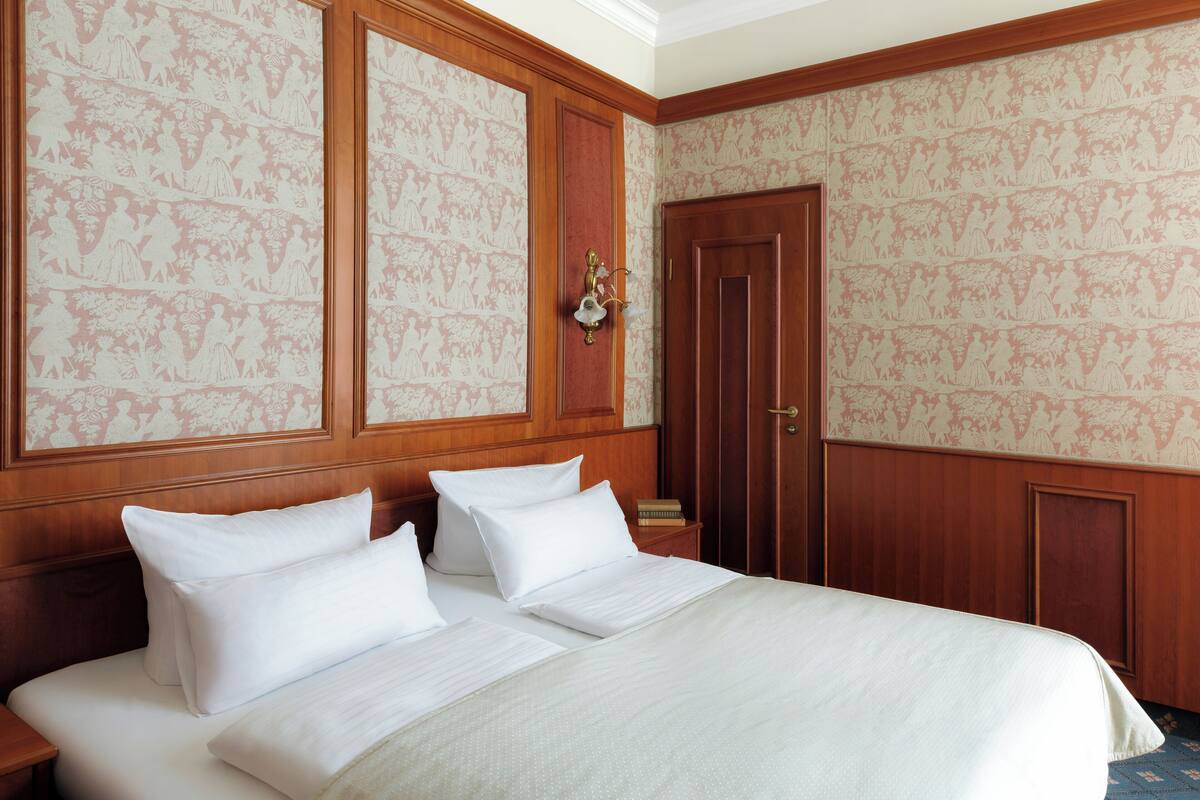 Ein Hotelzimmer mit einem großen Bett, einem Holzkopfstück und einer Tür mit einem Spiegel.