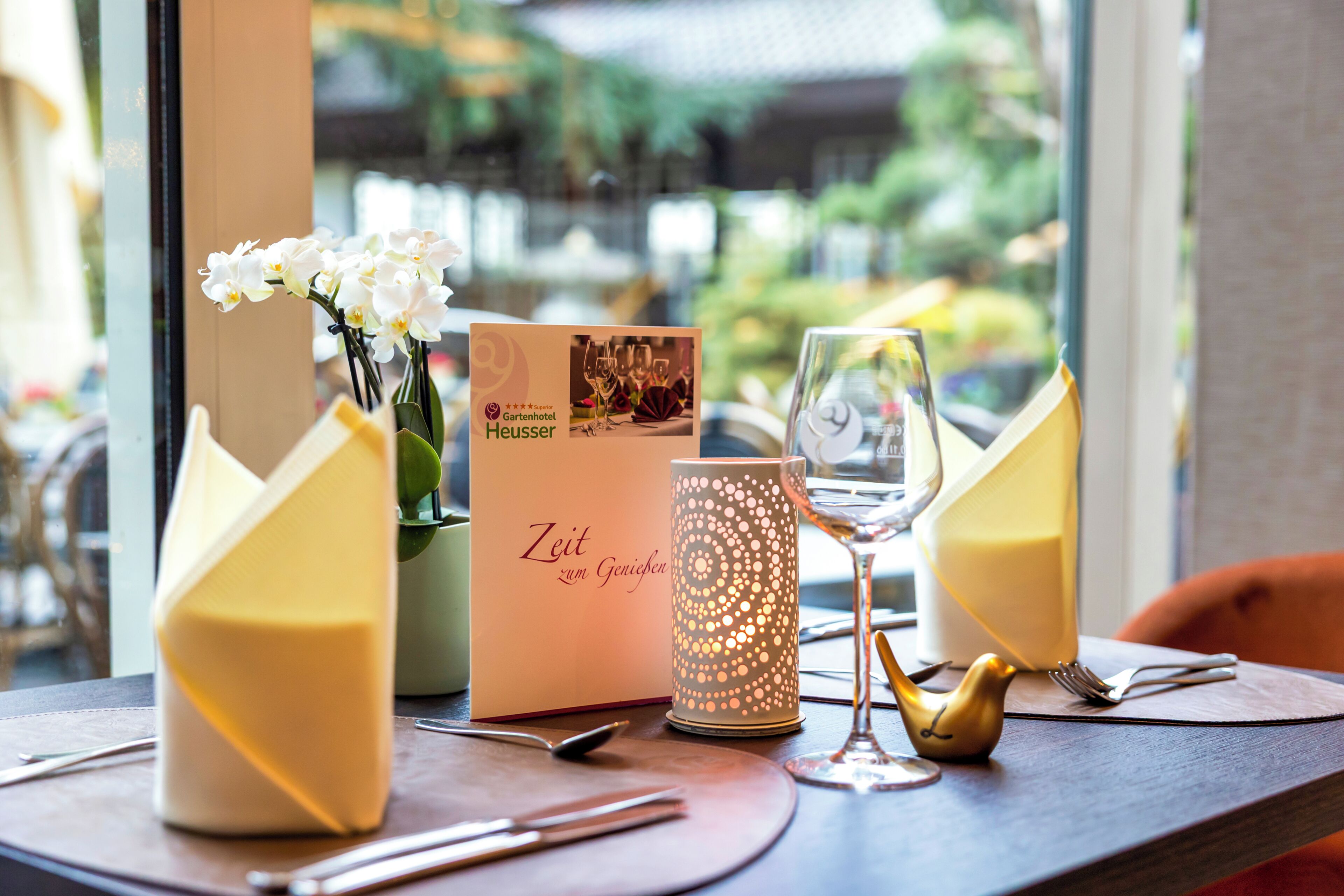 A table set with a menu, a candle, and a decorative bird.