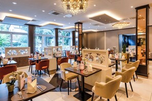 A restaurant with tables, chairs, and a chandelier. - Gartenhotel Heusser (Bad Durkheim)