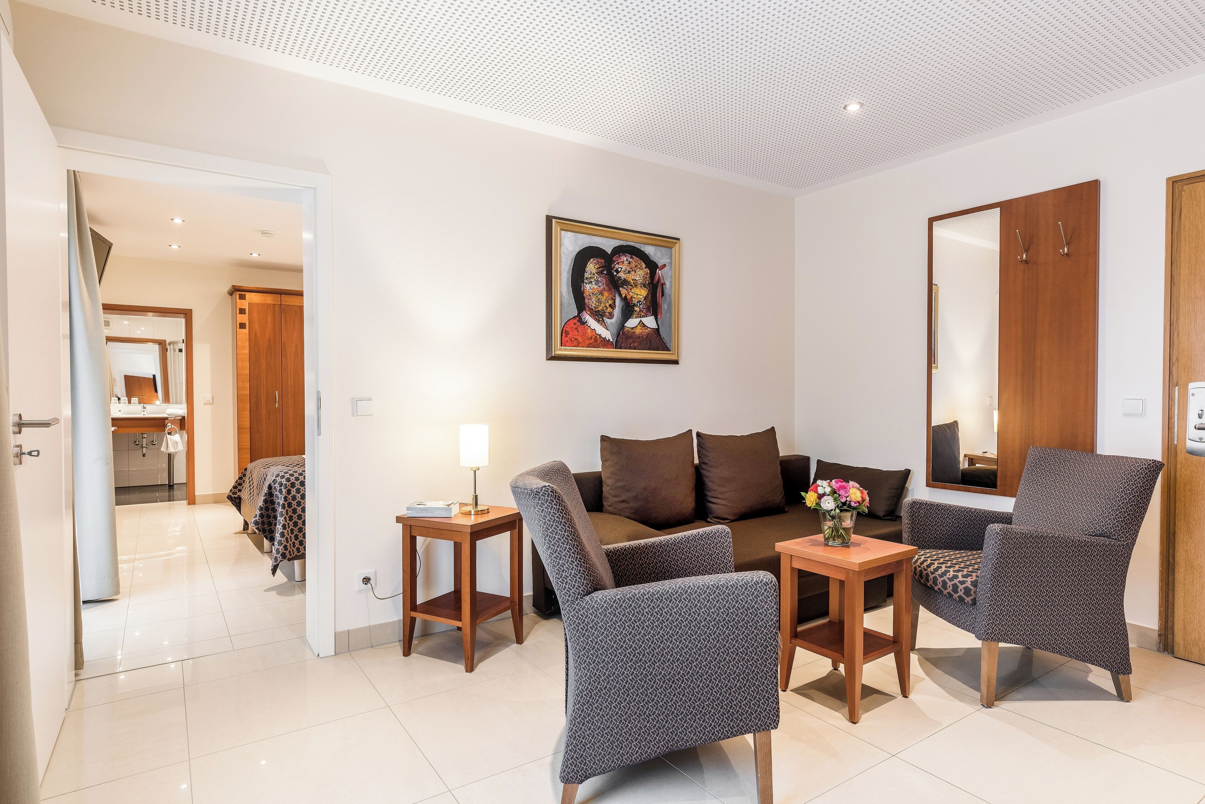 Una sala de estar moderna con un sofá, dos sillones, una mesita y un cuadro en la pared.