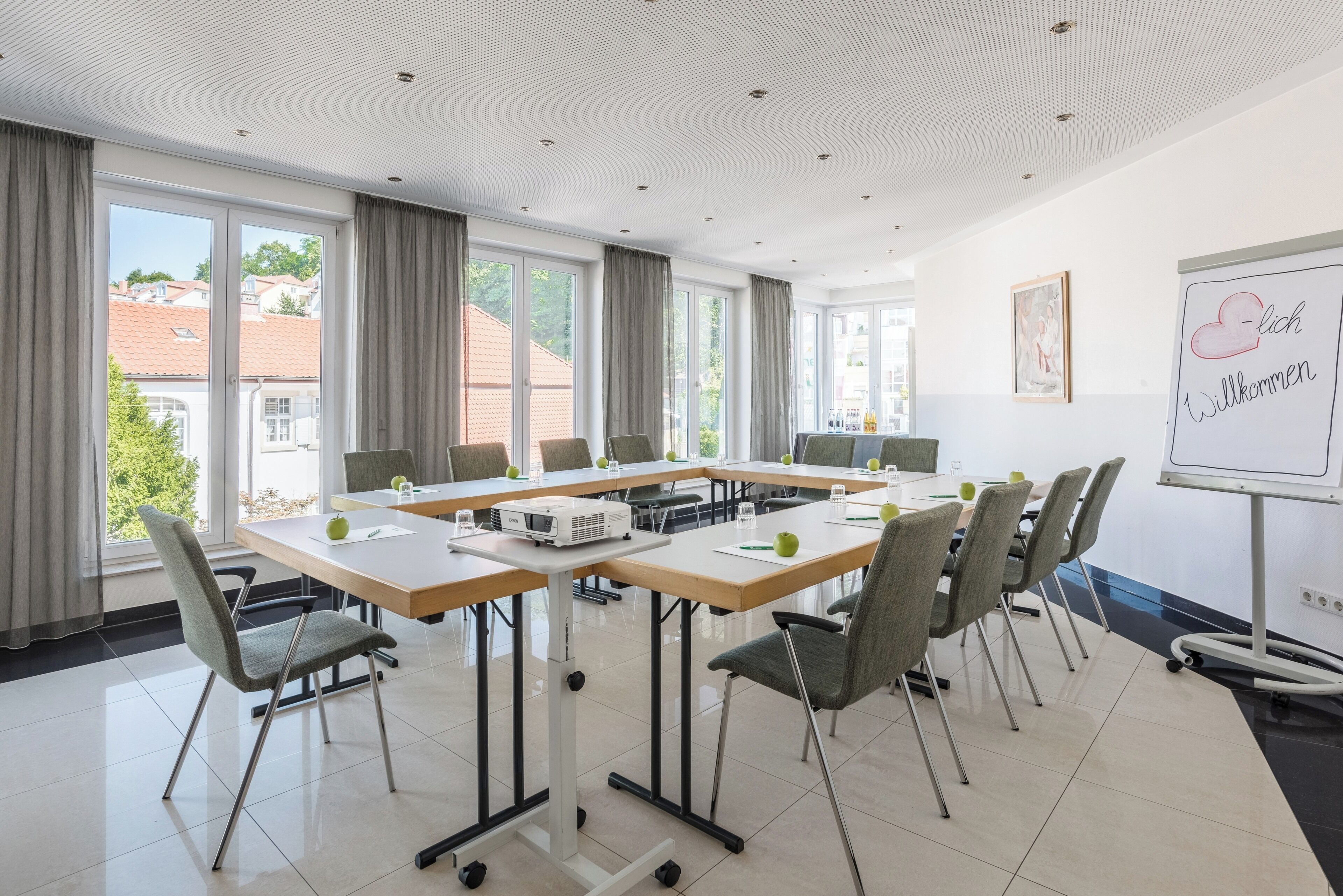 A conference room with a large table, chairs, a whiteboard, and a view of buildings outside.
