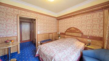 Ein Hotelzimmer mit einem Bett, einem Schreibtisch, einem Stuhl und einem kleinen Tisch mit Früchten.