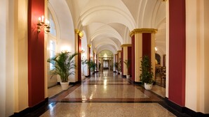 A grand hallway with arched ceilings, red and white walls, and potted plants. - Häcker's Grand Hotel Bad Ems (Bad Ems)