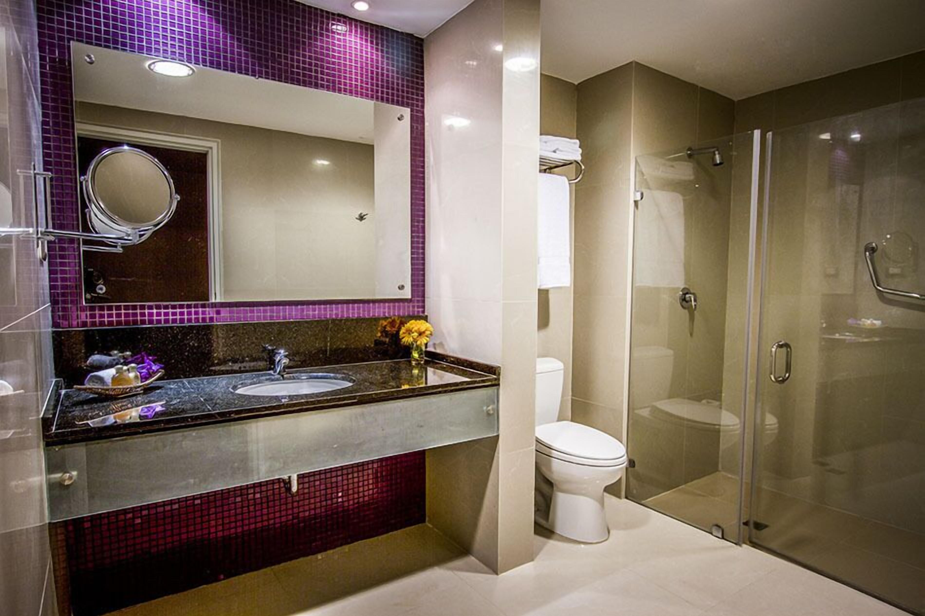 Une salle de bain moderne avec une douche à parois de verre, un lavabo avec un miroir et des toilettes.