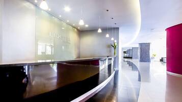 A modern hotel reception area with a curved reception desk, glass walls, and pendant lighting.
