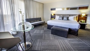 Una habitación de hotel moderna con una cama grande, una mesa de vidrio, un sofá y un banco.