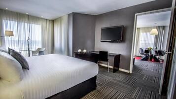 Quarto de hotel moderno com uma cama grande, uma escrivaninha, uma televisão de tela plana e um espelho.